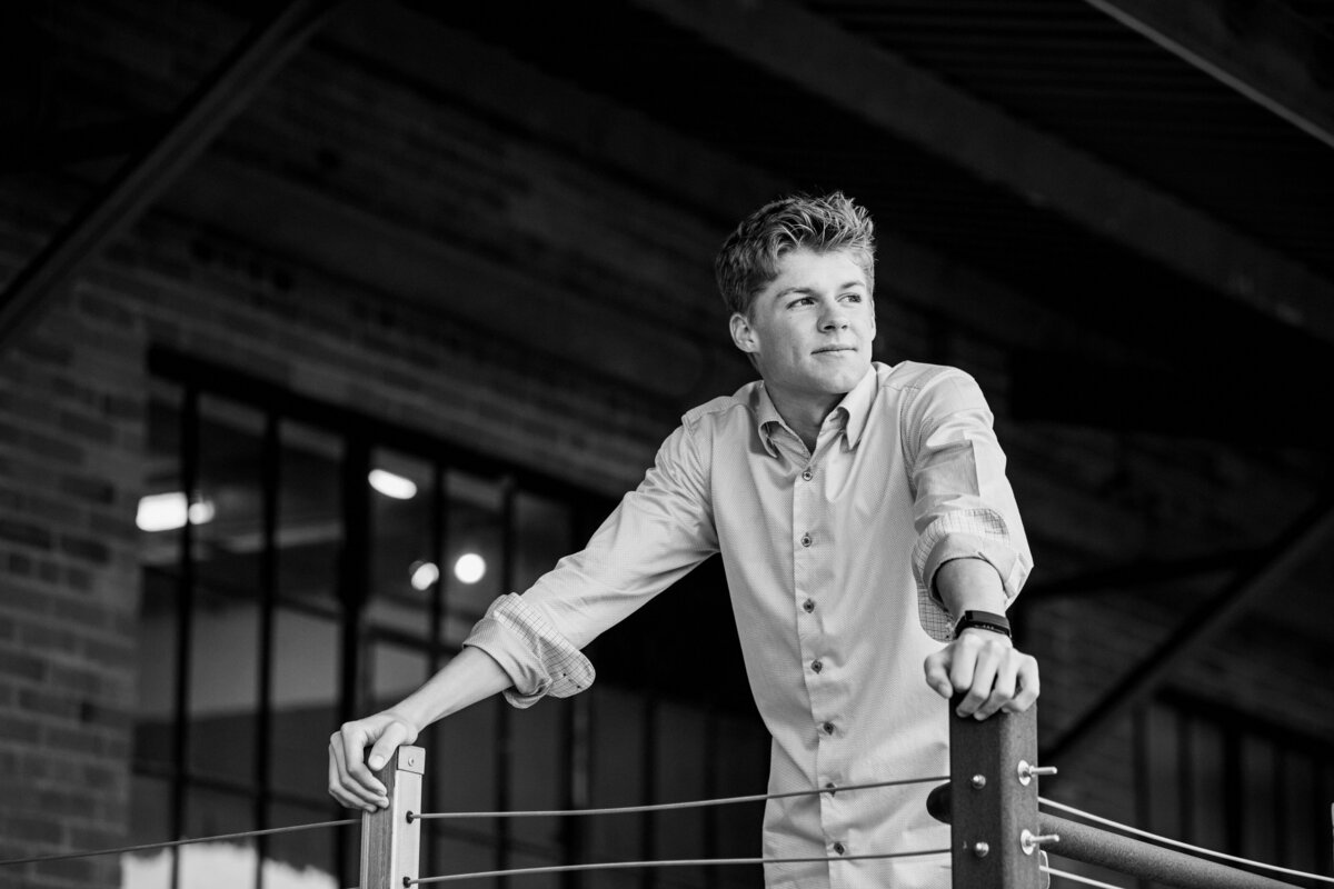 black and white photo of high school senior leaning against railing