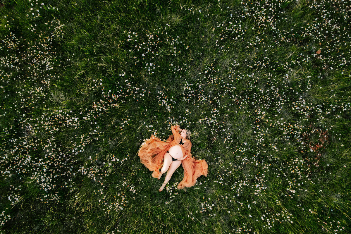 pregnant mom in floral dress hugging belly at a field captured by Springfield MO maternity photographer Jessica Kennedy of The XO Photography