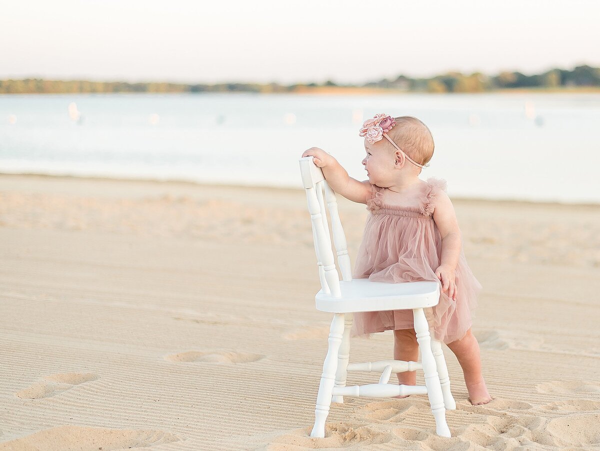little girl holding onto a chair at the beach