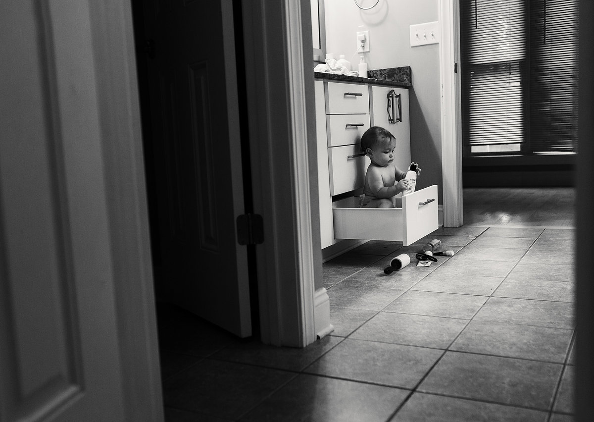 charlotte documentary photographer jamie lucido captures a candid image of a toddler sitting in a bathroom drawer