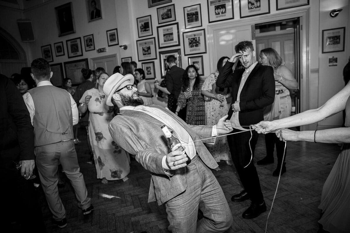 Man wearing hat is being pulled  by string around his waist on dancefloor