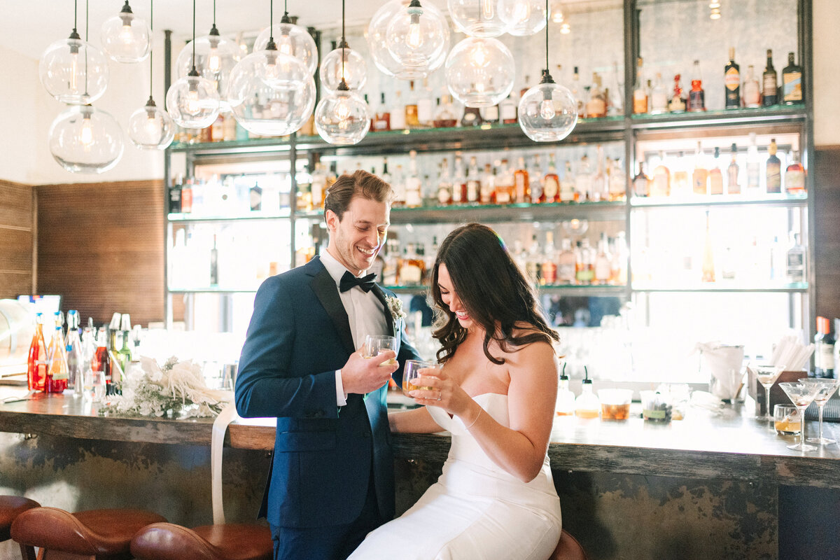 bride and groom share a drink at the bar