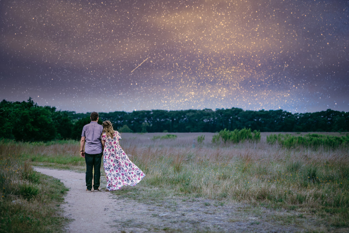 Engaged couple staring off into the distance at a starry night sky while standing in an open field in Boerne, Texas