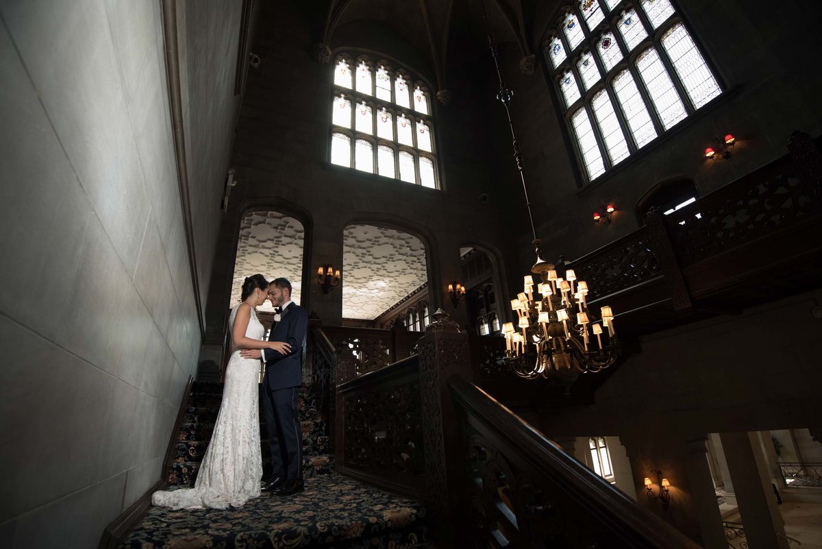 Bride and groom in each other's arms at the top of the stairs at Hempstead House