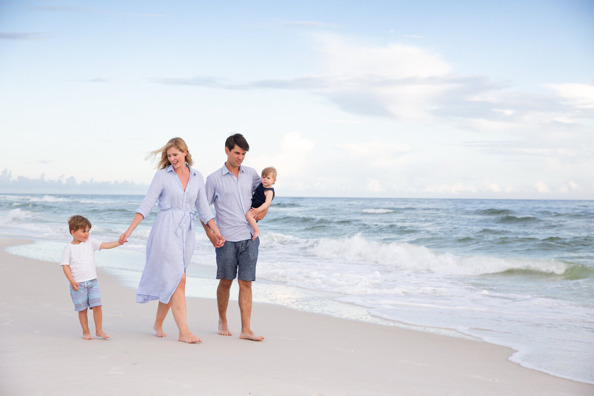 A family smiling as they walk along the water