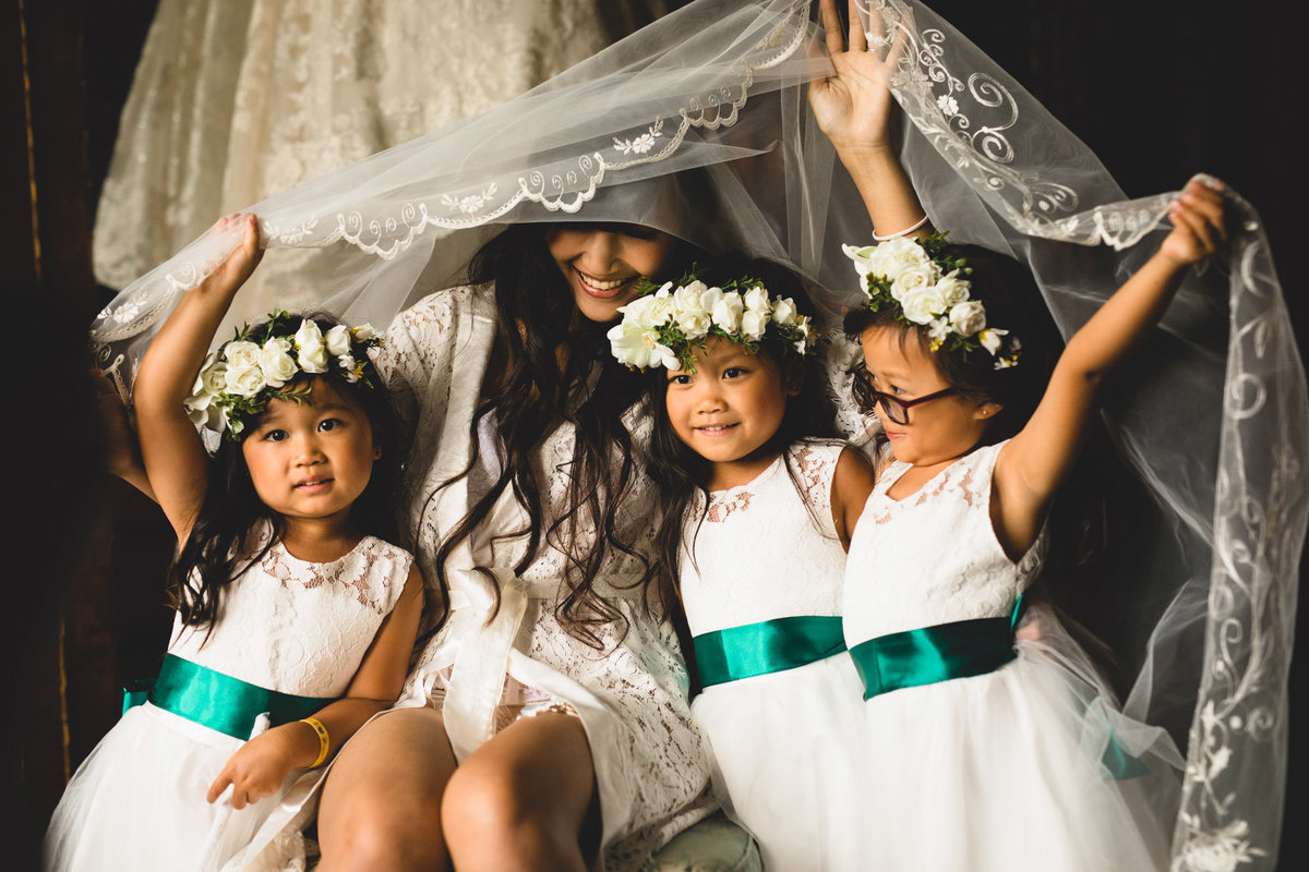 bride and flower girls playing with the veil
