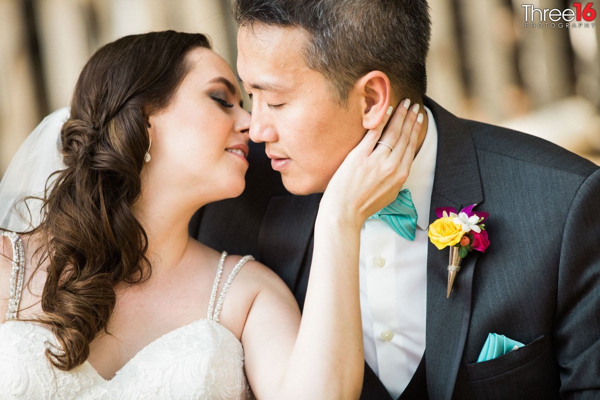 Bride reaches back and places her hand on her Groom's cheek just prior to a tender kiss