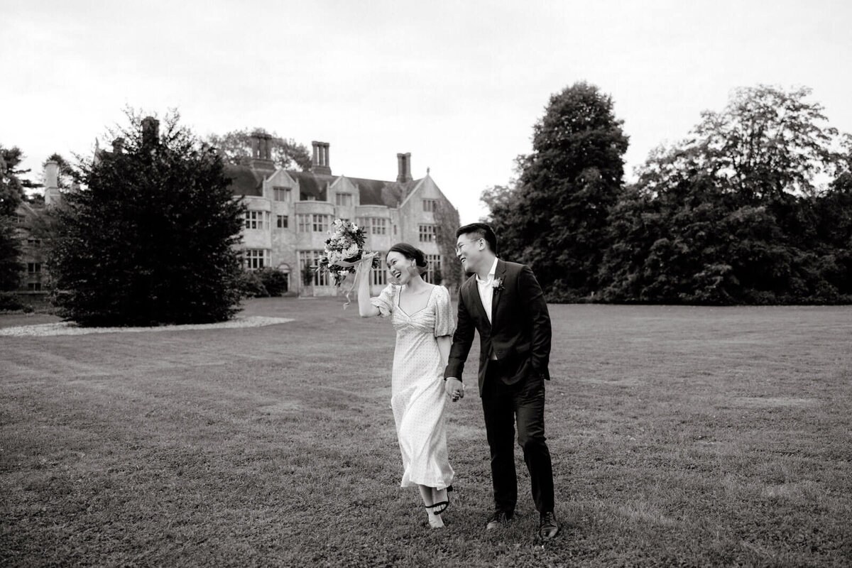 The engaged couple are happily walking in the vast lawn outside Coe Hall at Planting Fields Arboretum, NY. Image by Jenny Fu Studio