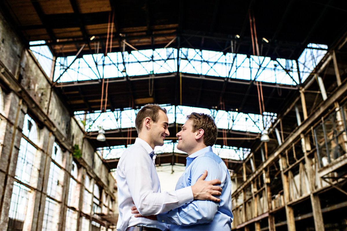 A same sex couple hug in an abandoned warehouse in baltimore, md.