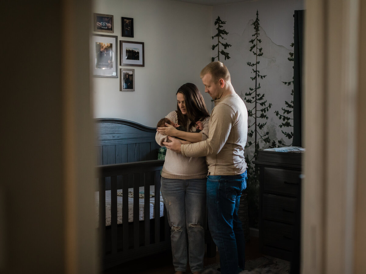mom and dad holding newborn son in nursery for in home lifestyle session