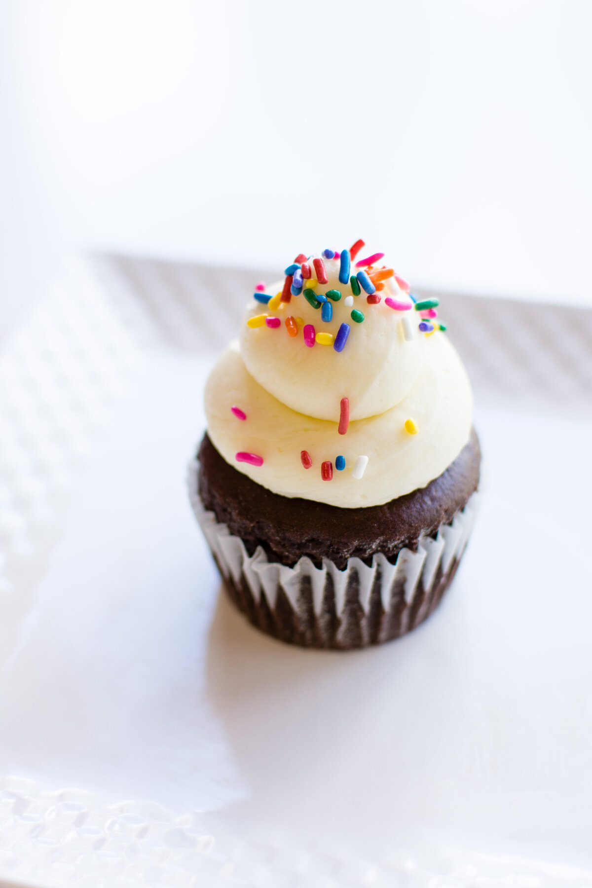 Chocolate cupcake with white icing and colorful sprinkles  on top