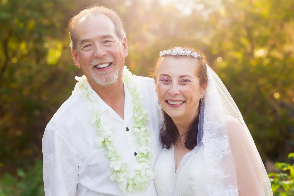 Portrait of mature couple smiling at the camera for their elopement portrait with greenery in the background at