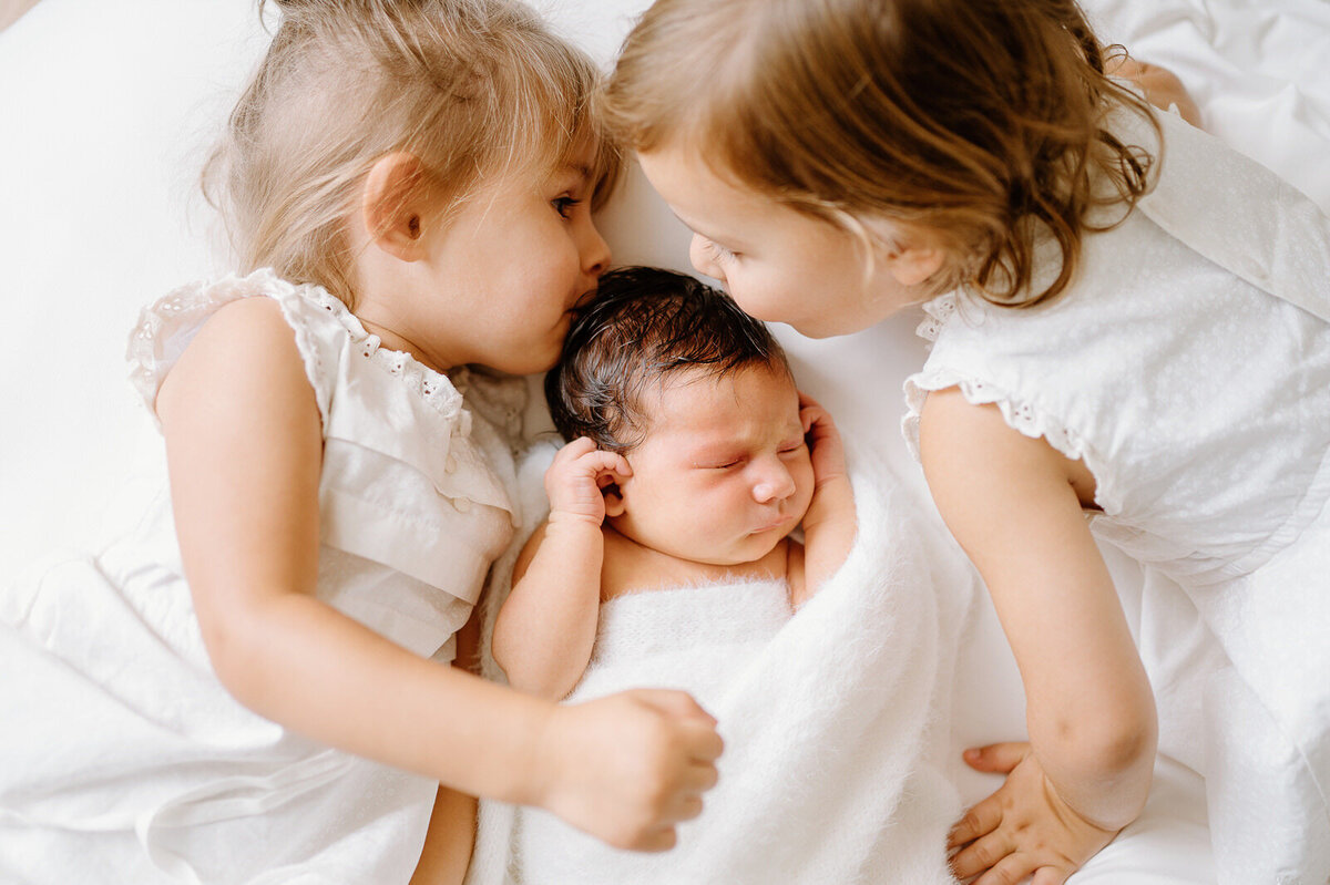 Twins giving kisses to newborn sibling