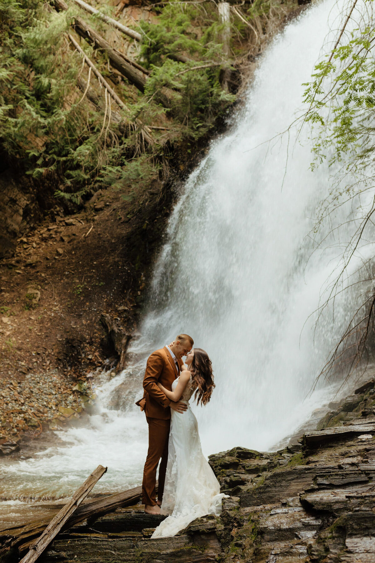 Stunning bride and groom kissing in front of waterfall, by Malorie Reiter Photography, adventurous and authentic wedding photographer in Lethbridge, Alberta. Featured on the Bronte Bride Vendor Guide.