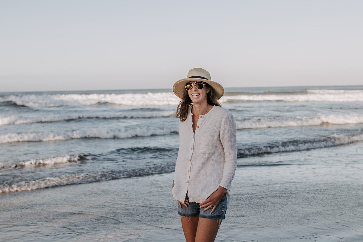 smiling casual woman in hat on beach