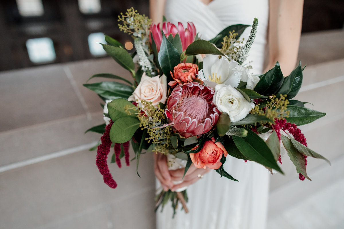 San Francisco bride holds her red white and pink flower wedding bouquet at SF City Hall