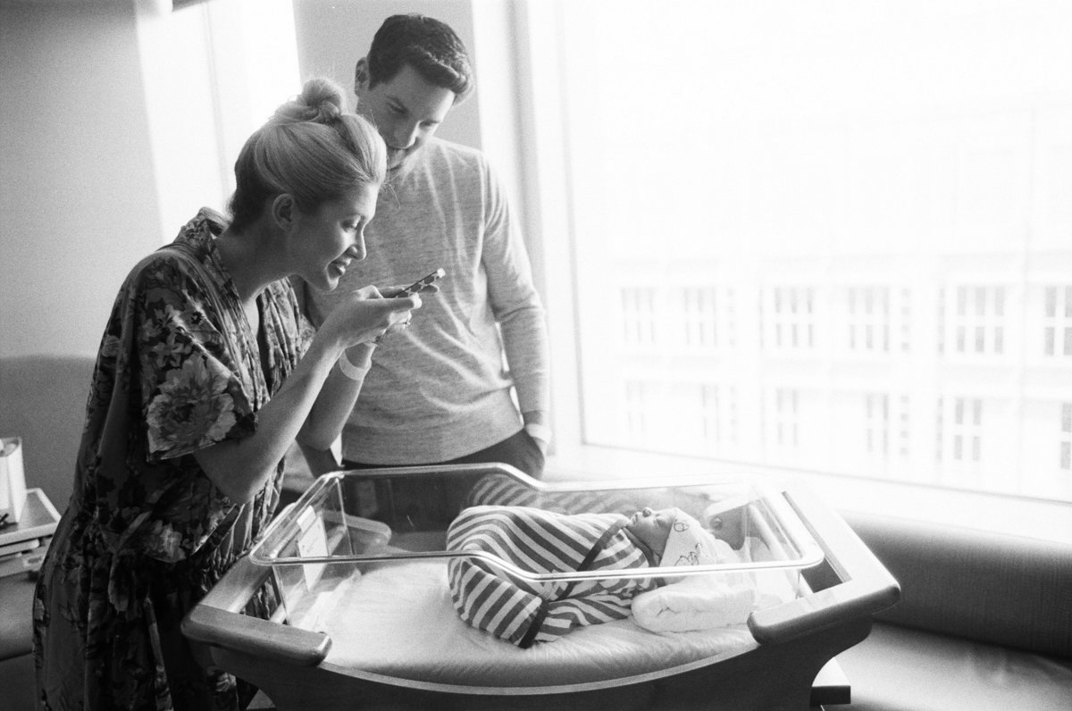 mother taking iphone picture of newborn baby