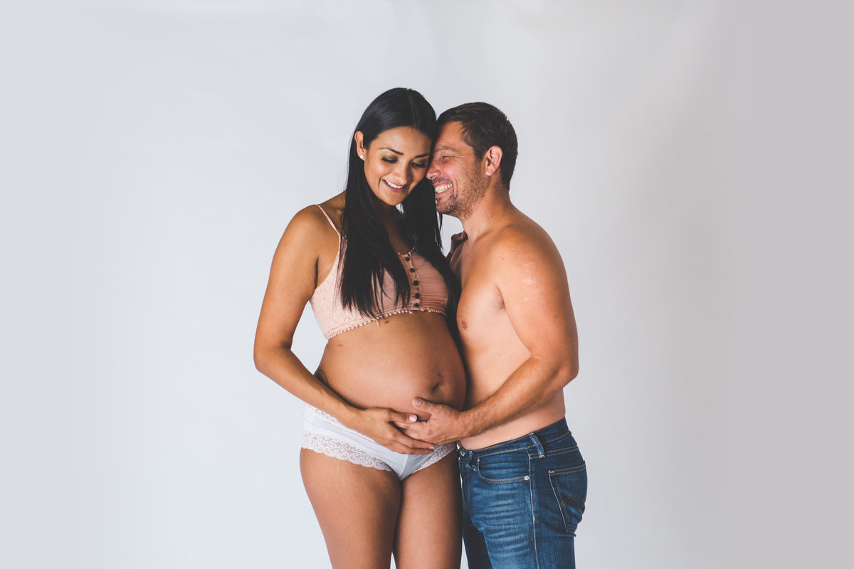 San Antonio Maternity photography in studio session of pregnant couple with man holding woman's belly.