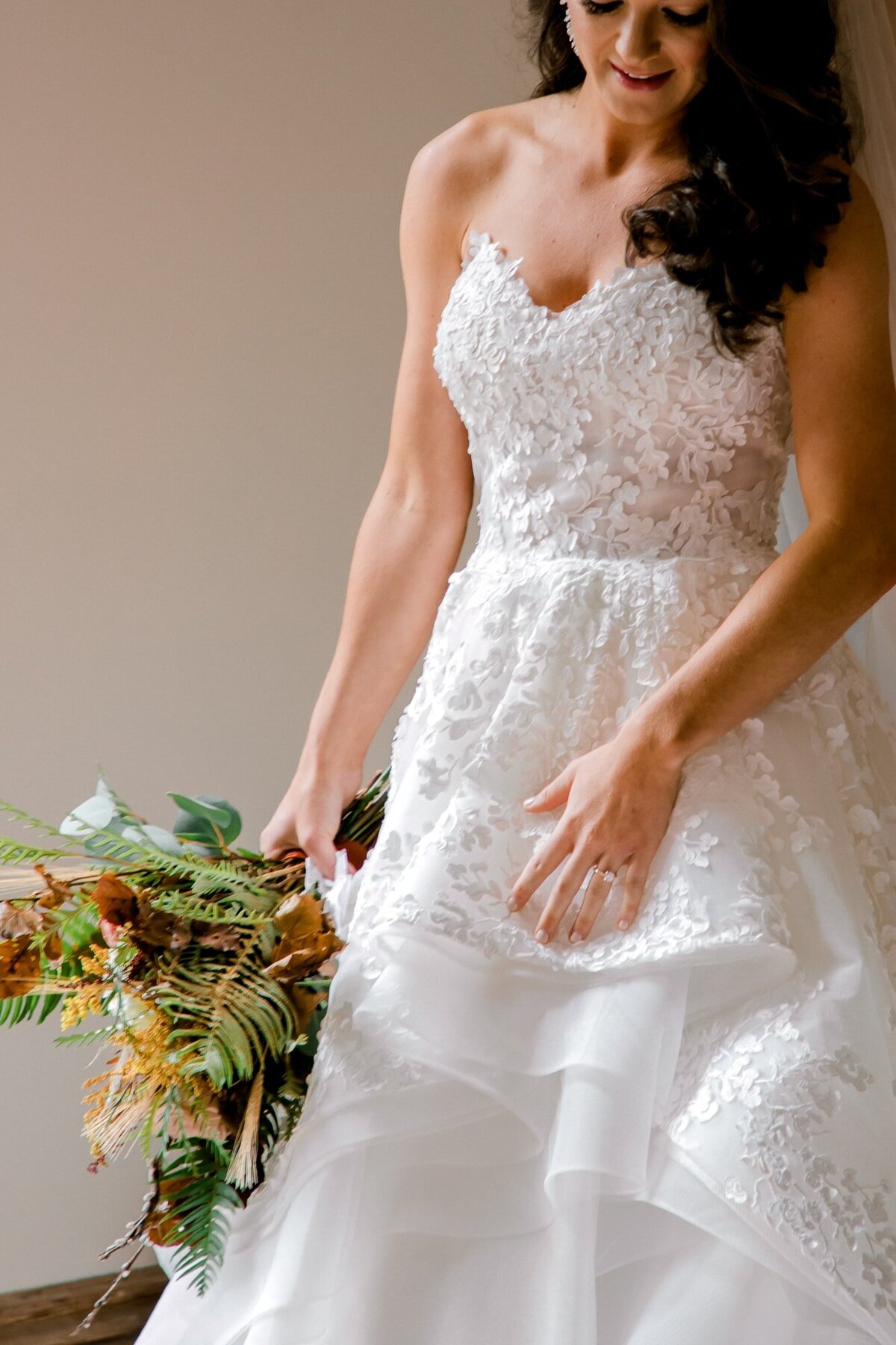 Bride in lace ballgown holding an organic bouquet