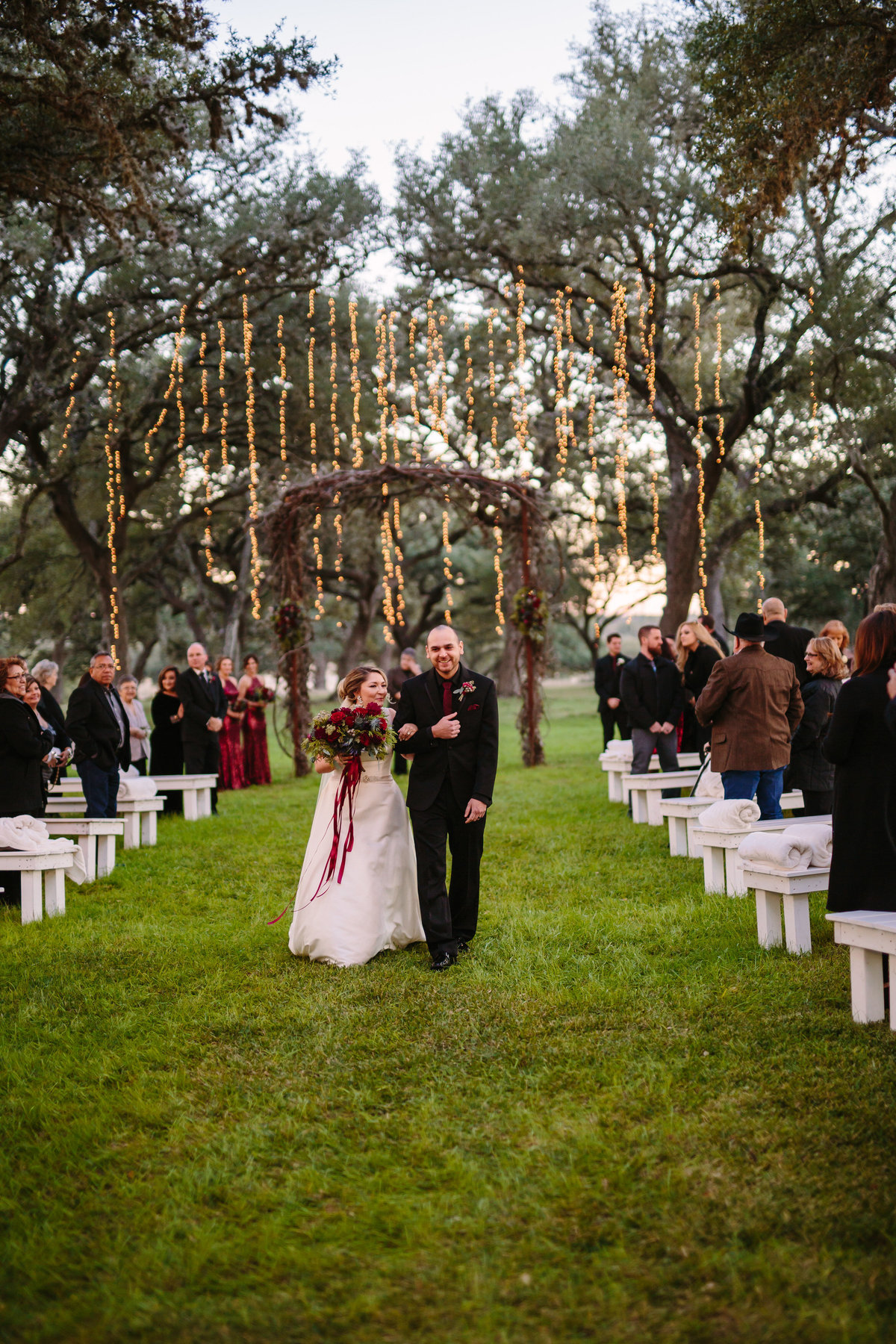 bride and groom exit lit Christmas wedding ceremony site Oaks of Boerne outdoor wedding venue in Texas
