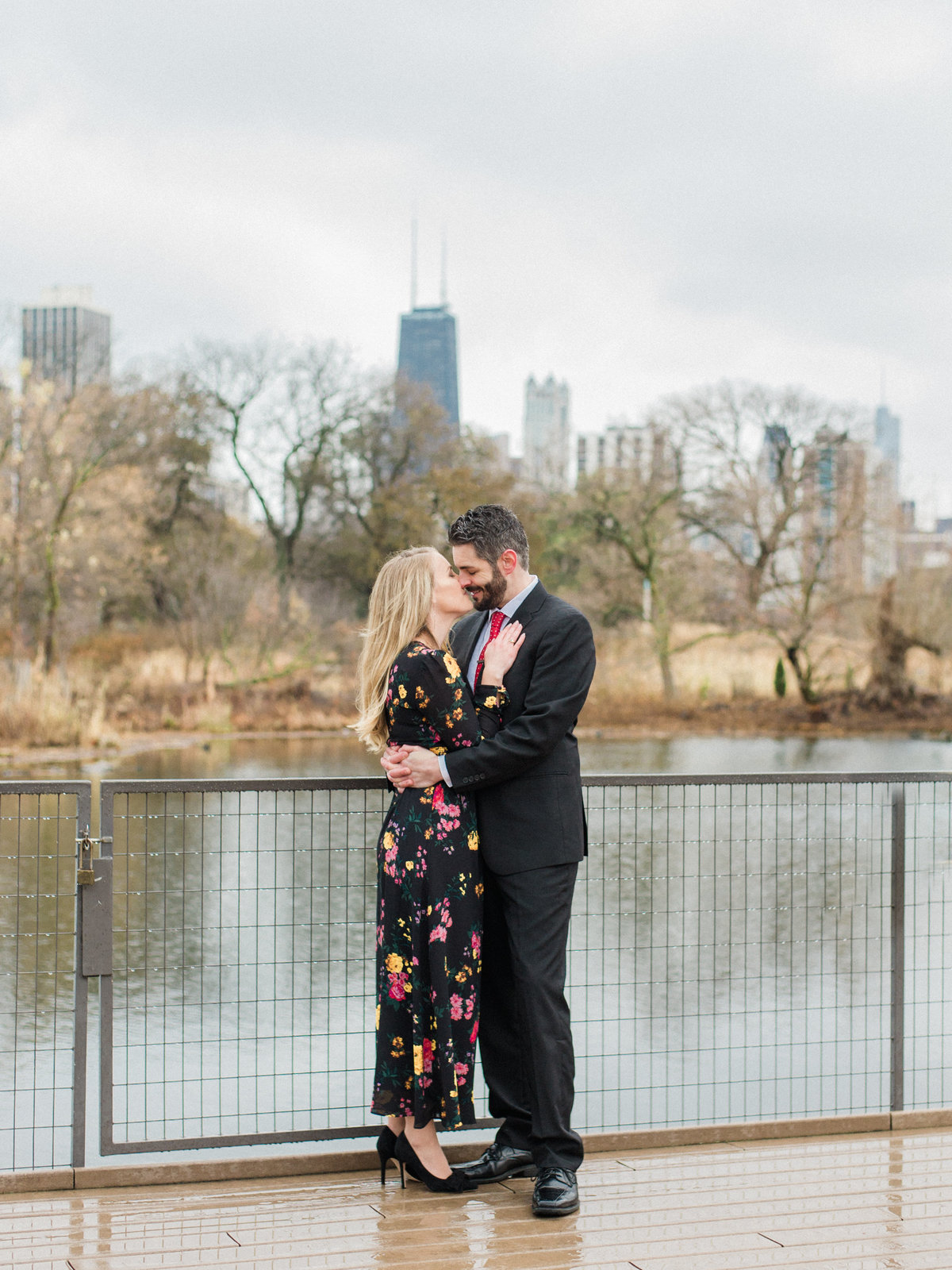 couple hugging on bridge wearing black gown and suit