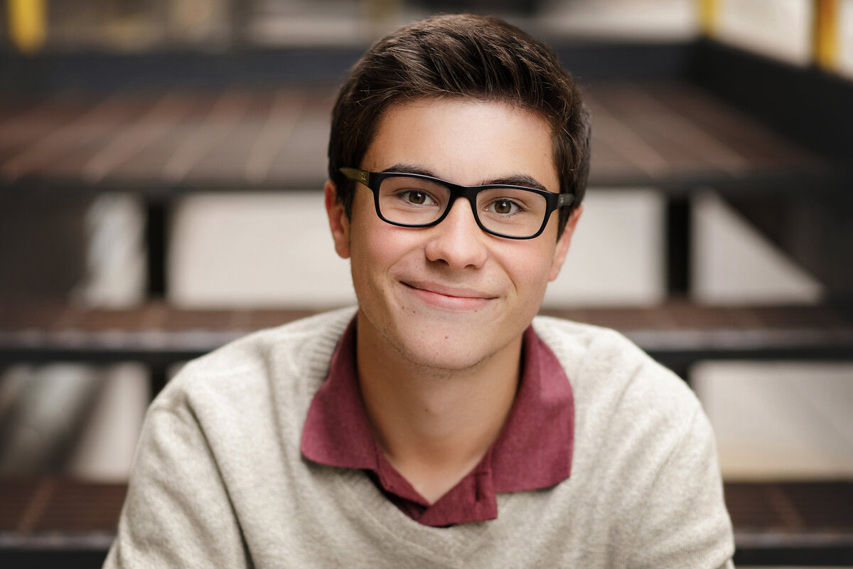 high school boy sitting on steps with glasses
