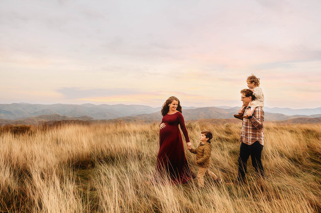 Family walks across a mountain top during Family Photoshoot at Max Patch in Asheville, NC.