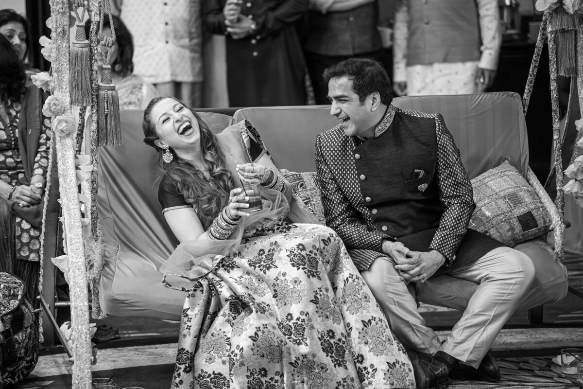 A candid Indian wedding photo. The bride and groom are sitting on swing.