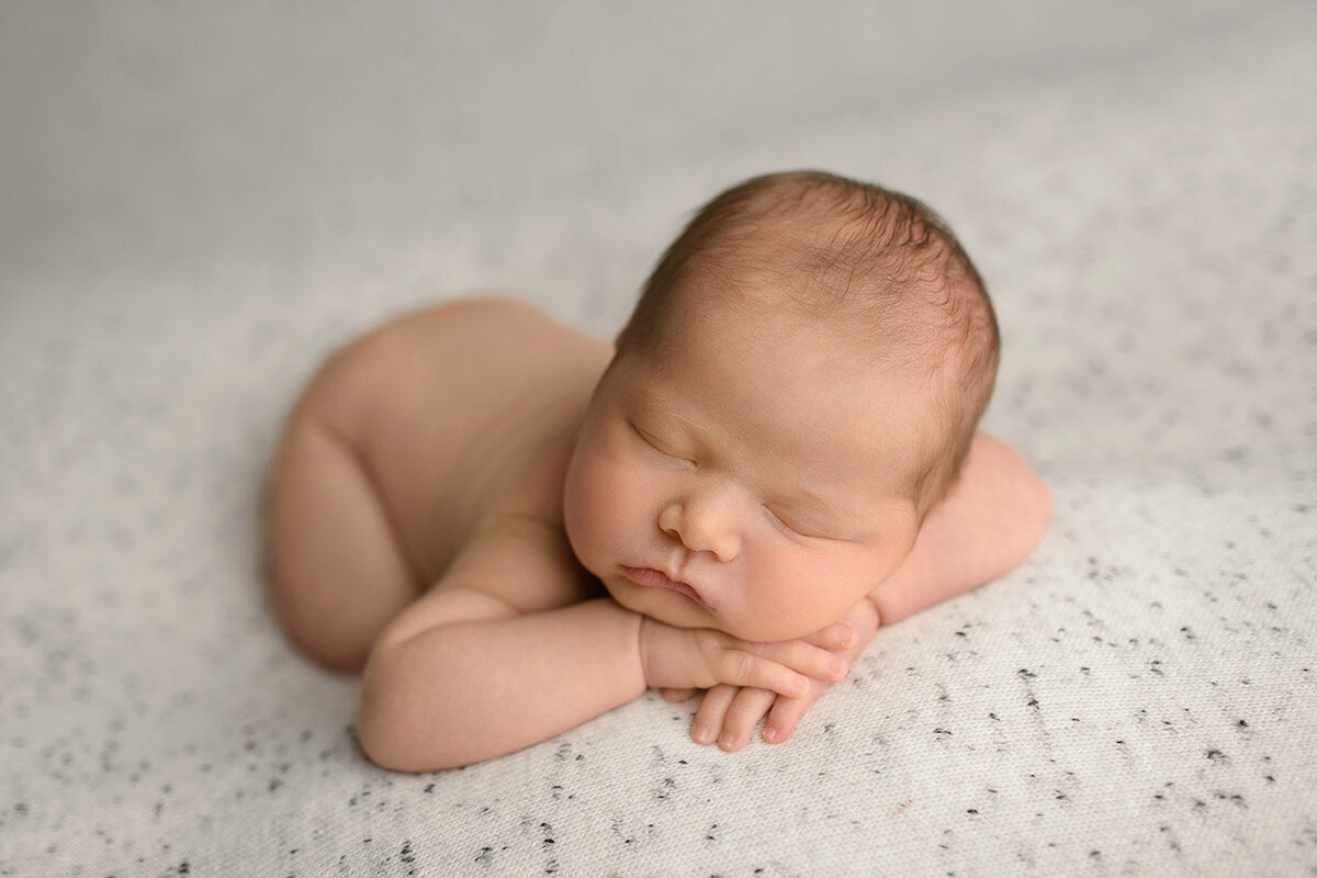 Sleeping newborn boy with hands under chin