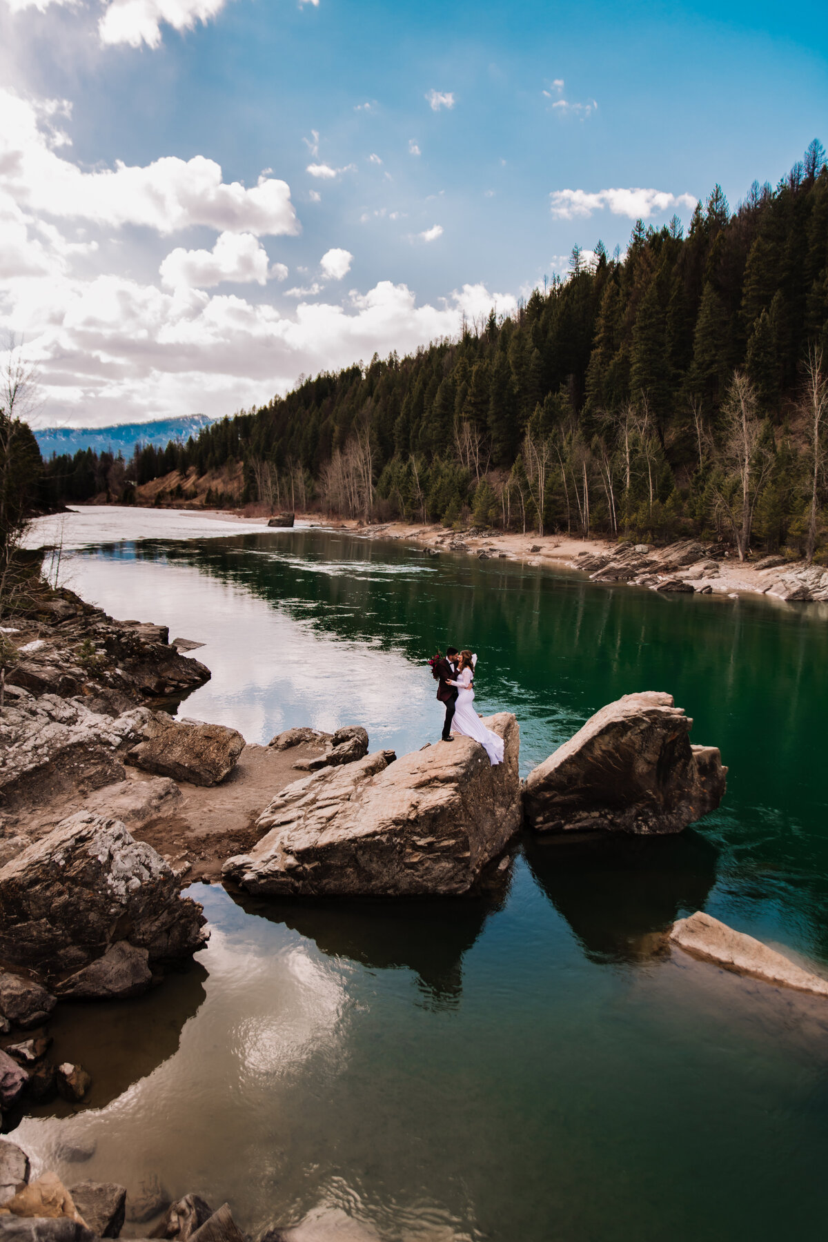 couple standing on rock near lake during adventure wedding