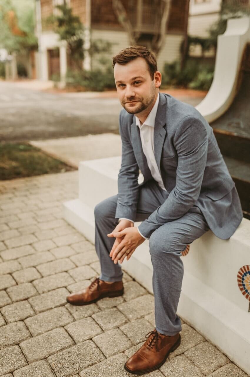 groom sits relaxed on edge of fountain after exchanging private vows