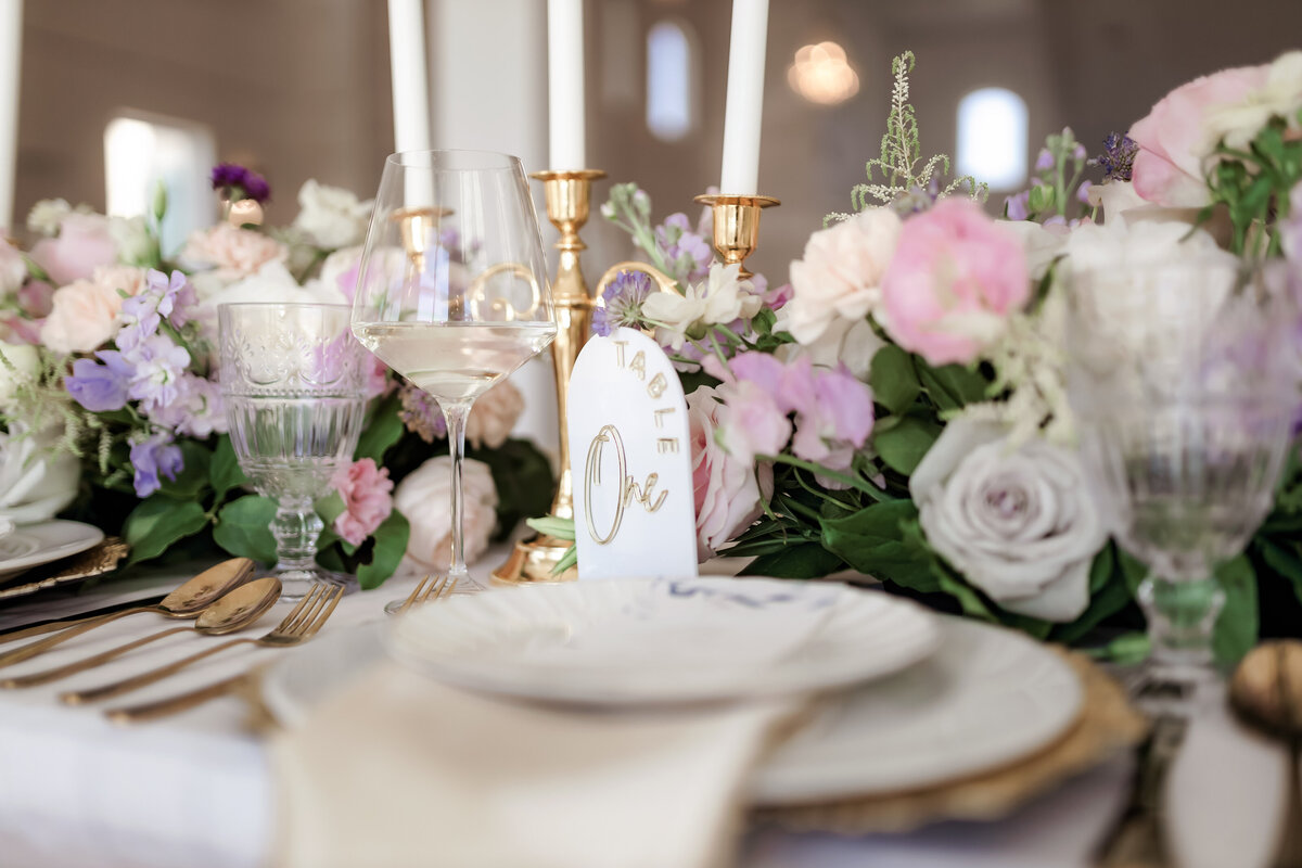 Table setting with lavender, pink and white floral  centerpieces and golden candelabras