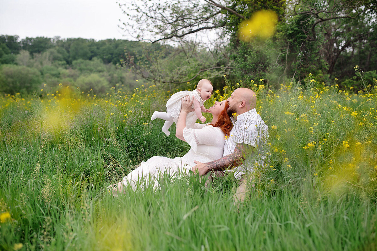 Family session of family sitting in a field of flowers