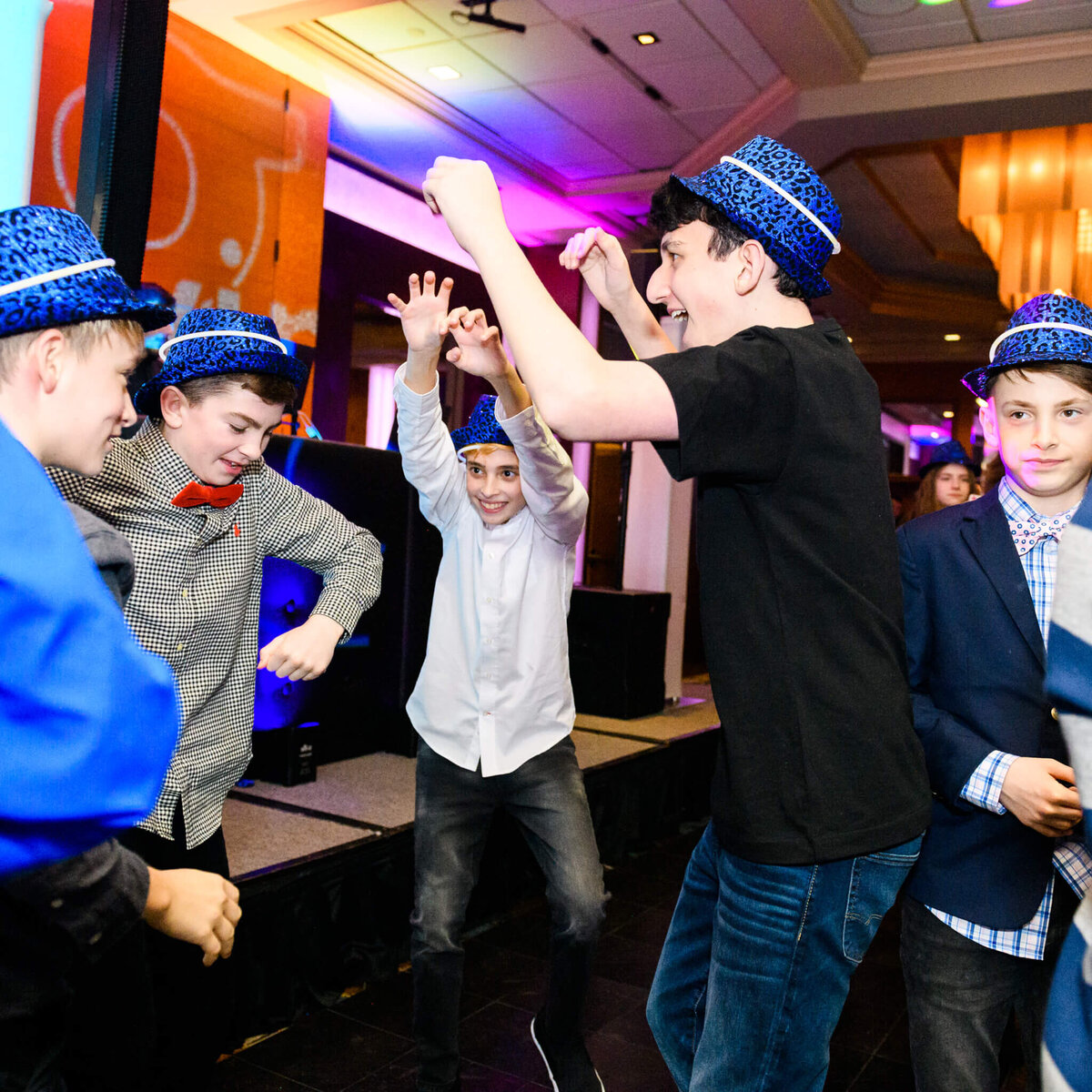 A group of teen boys dance and play in blue hats on a dance floor for some Bellevue Bar and Bat Mitzvah Photography