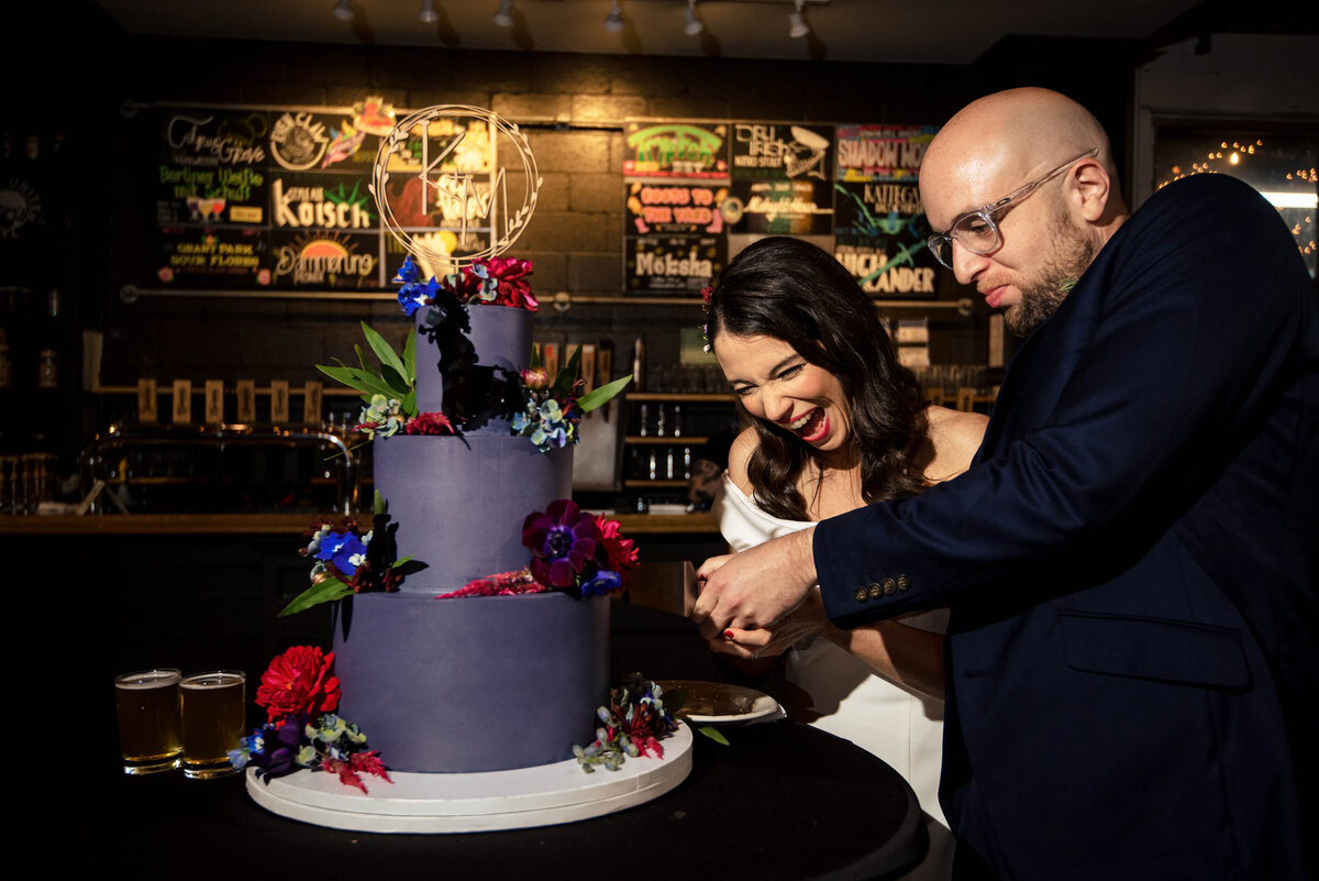 Candid-photograph-of-a-bride-and-groom-excitedly-cutting-their-cake-at-Eventide-Brewing-in-Atlanta-GA