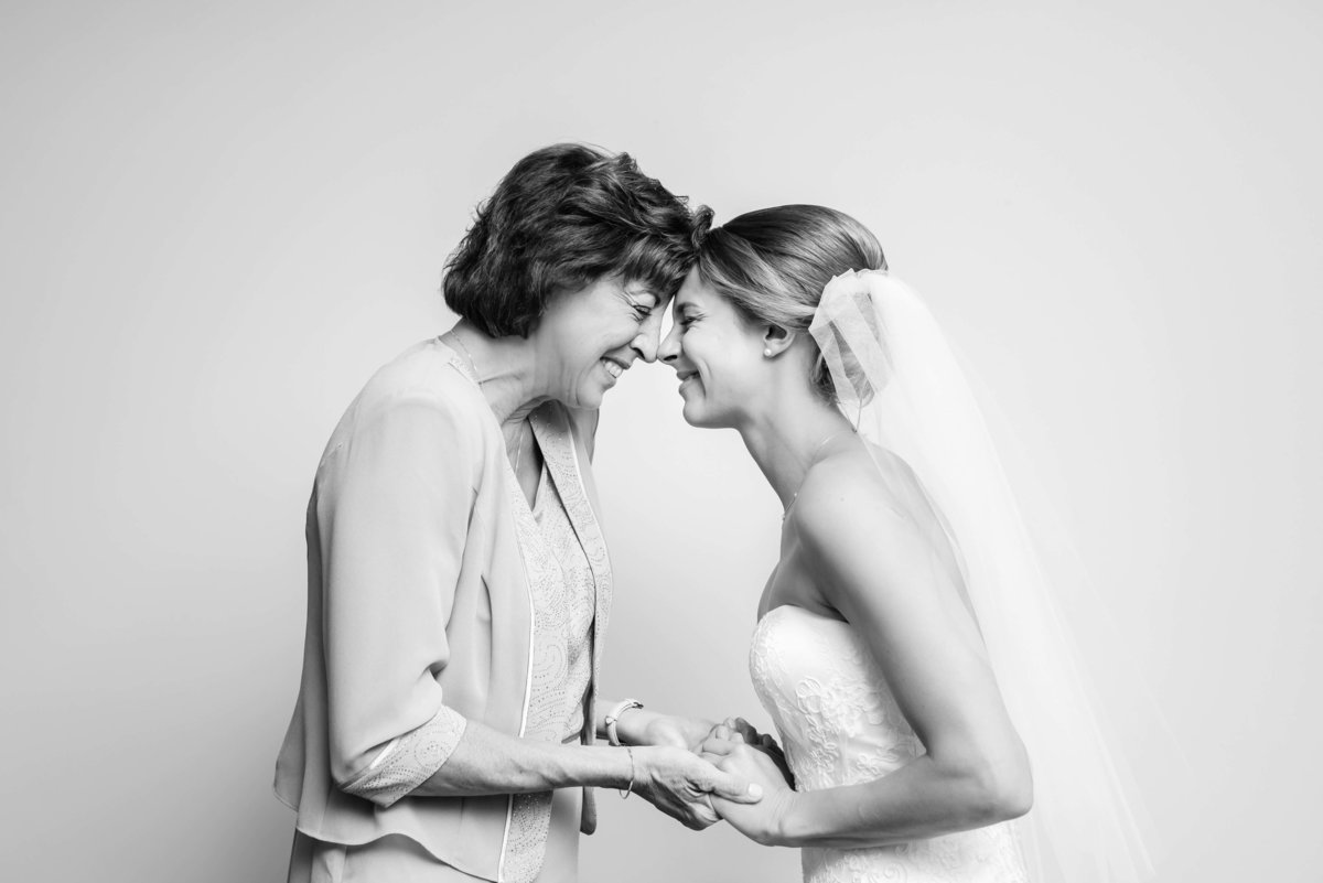 Mother of the Bride shares a tender moment leaning forehads together with her daughter before the wedding ceremony