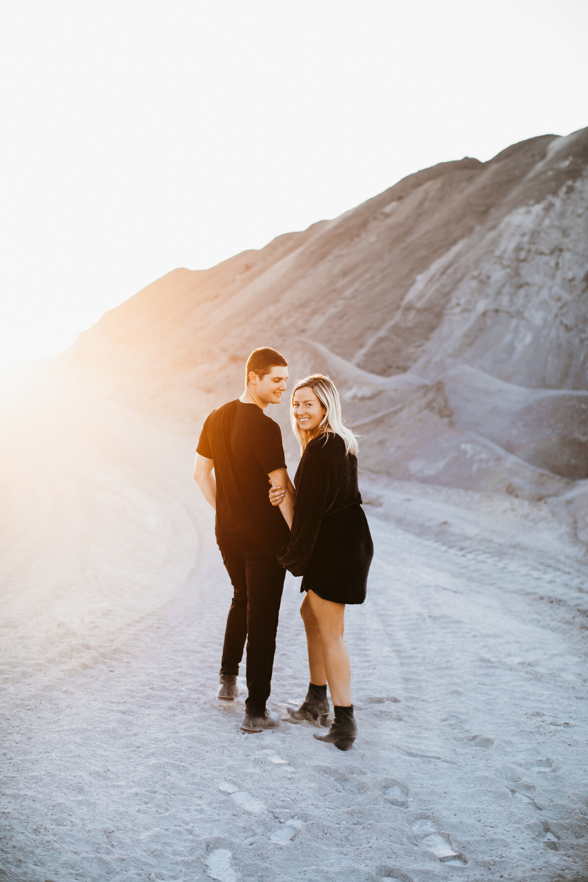 couple walking in the sand at sunset smiling