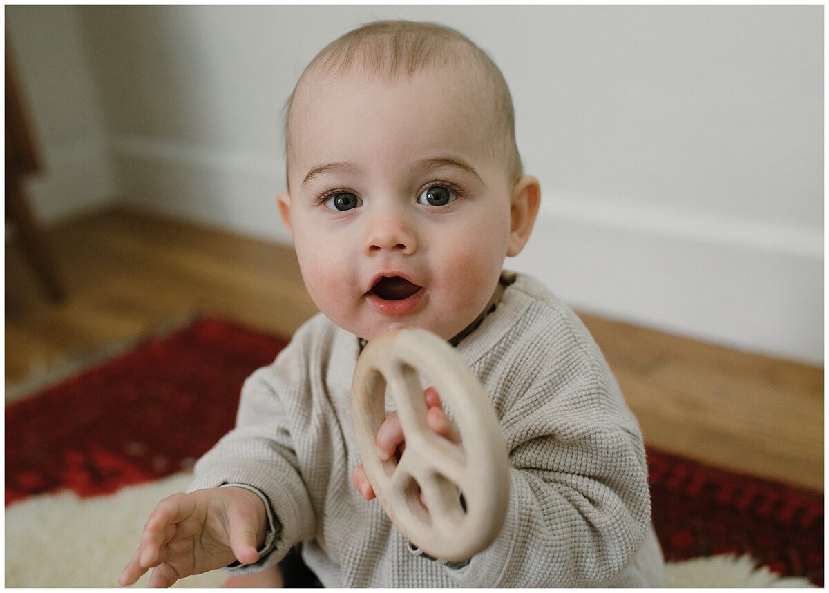 Baby holding a teething ring sitting on furry rug at sweet home family session in Austin by Amber Vickey Photography