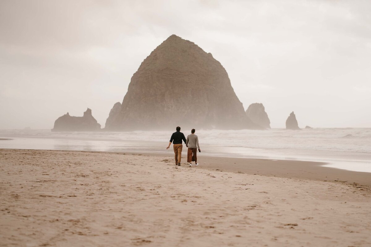 a couple walking together on cannon beach in seaside oregon