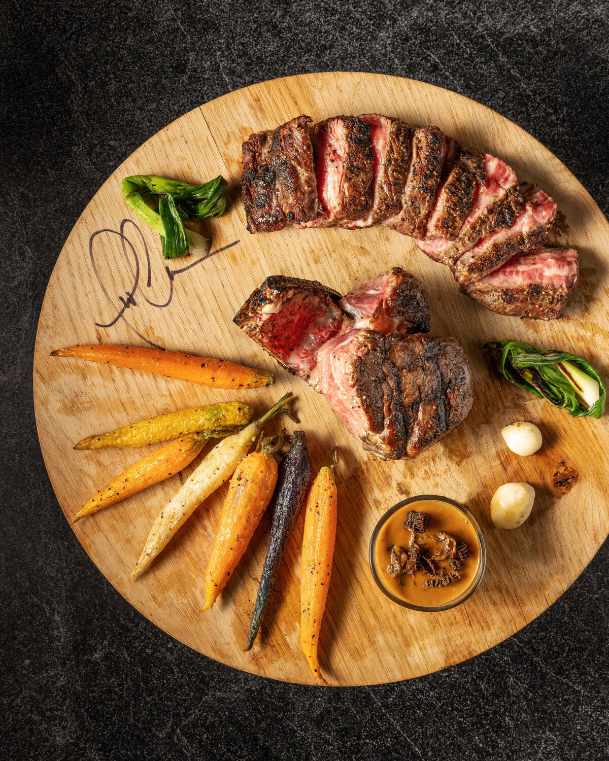 Steak and vegetable laid out on a wooden plank