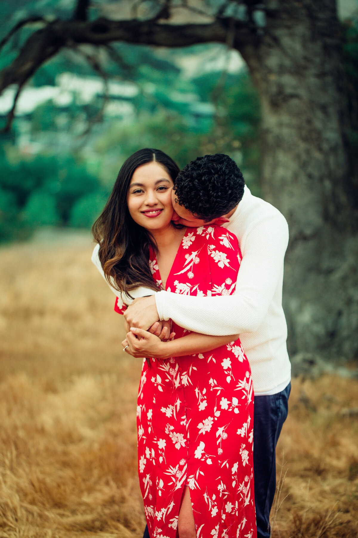 Engagement Photograph Of  Man In White Long Sleeves Hugging a Woman In Red Dress Los Angeles