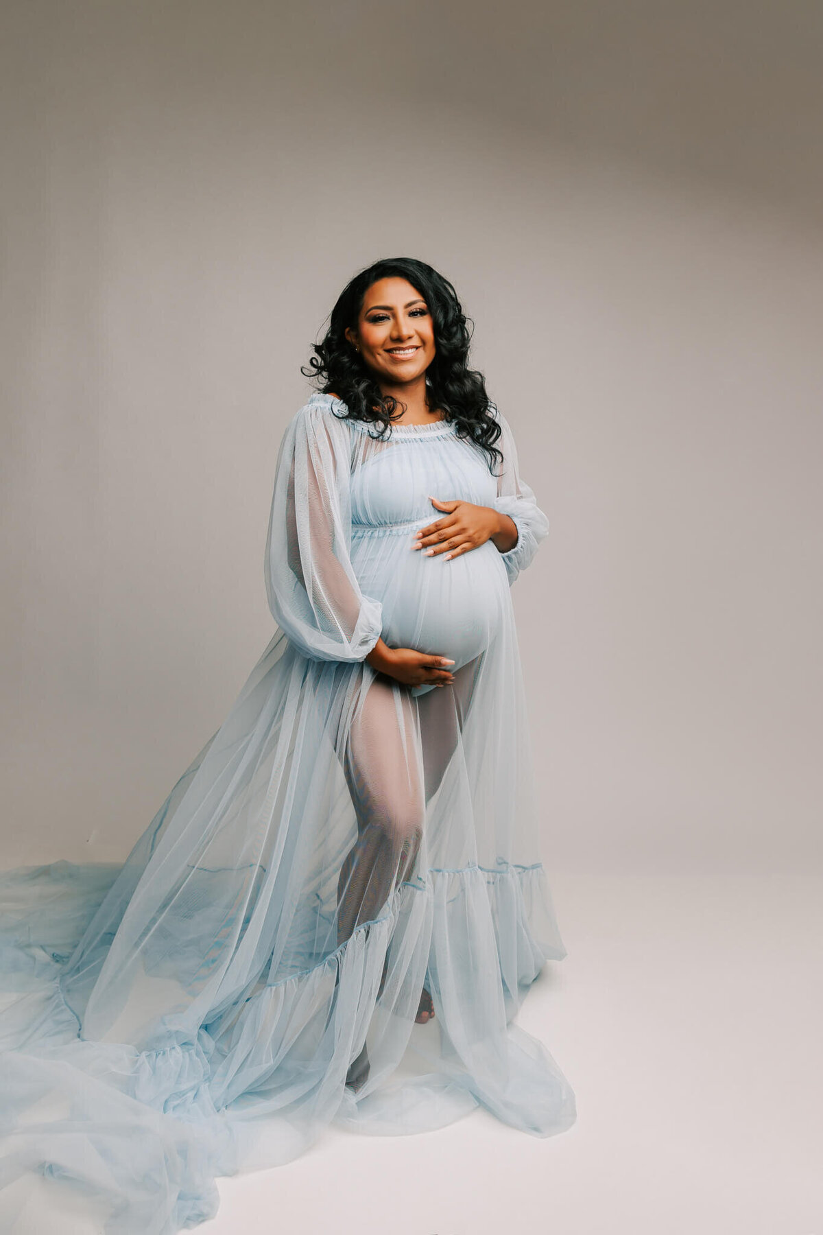 portland woman posing for studio maternity photography  wearing a blue dress