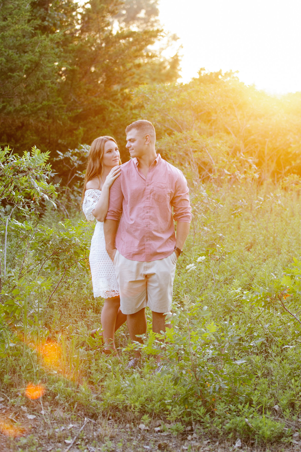 engaged couple stand in field at sunset in manasquan