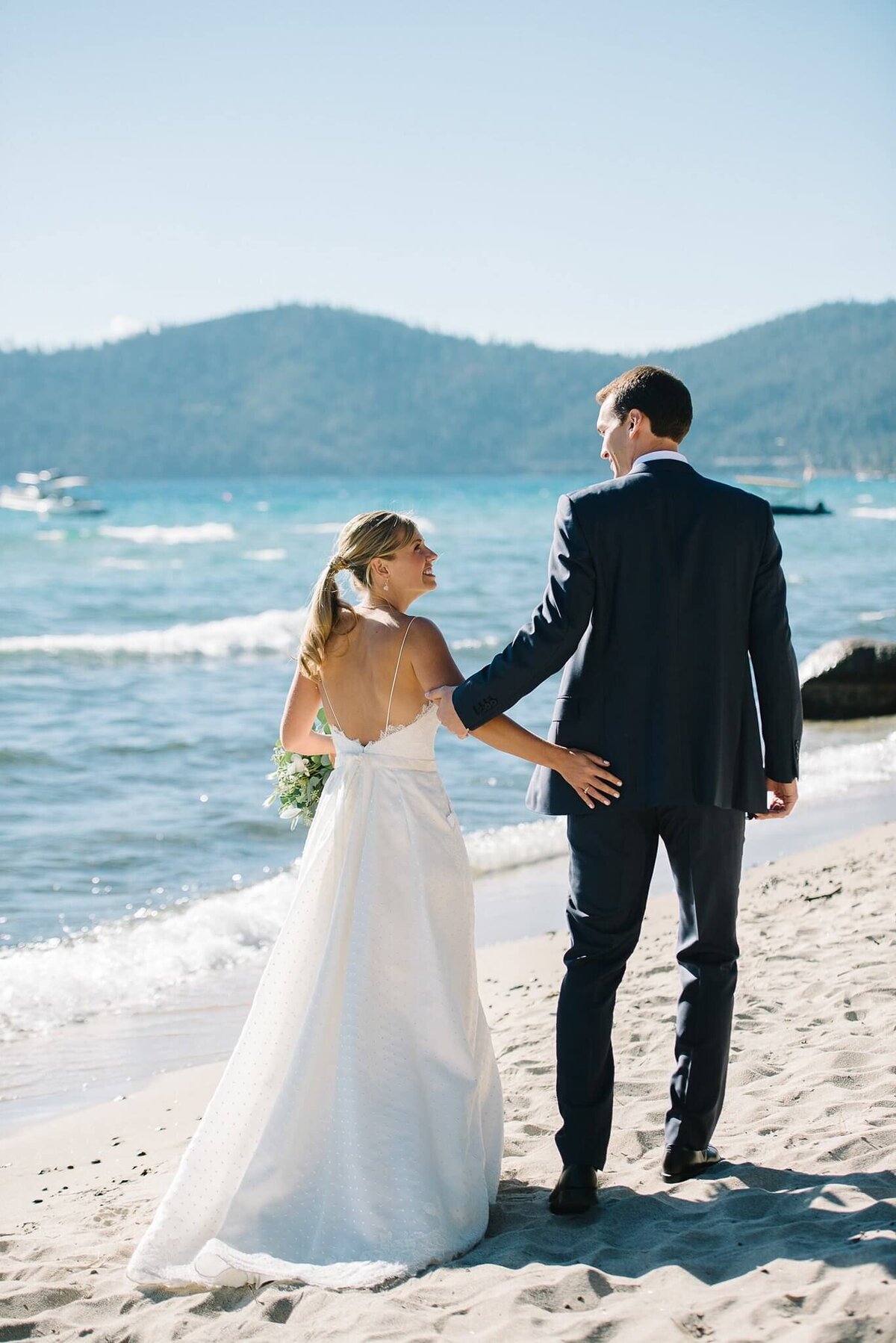 bride and groom on beach Lake Tahoe walking at Hyatt Tahoe wedding