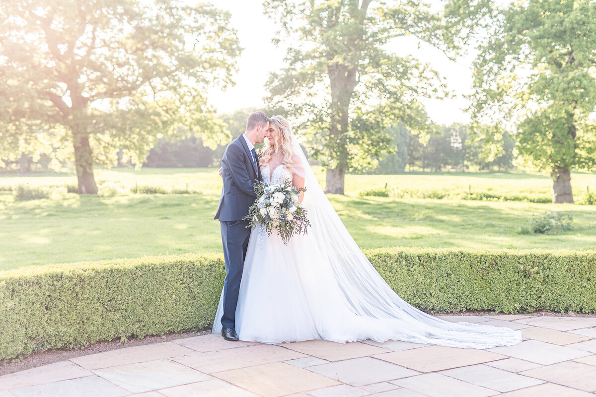 Bride and groom embracing touching foreheads in the grounds at Merrydale Manor Cheshire