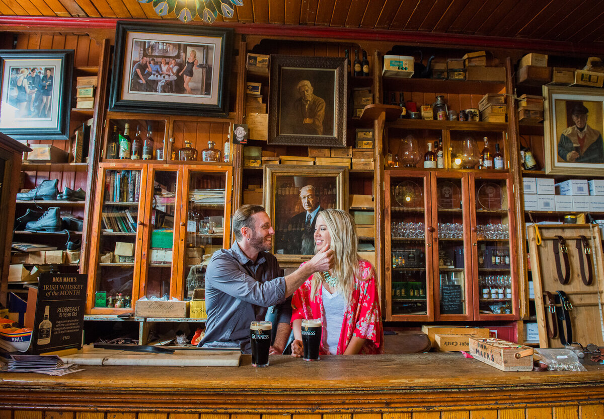 Young couple in colourful clothes sitting in an old Irish Pub in Dingle with pints of Guinness