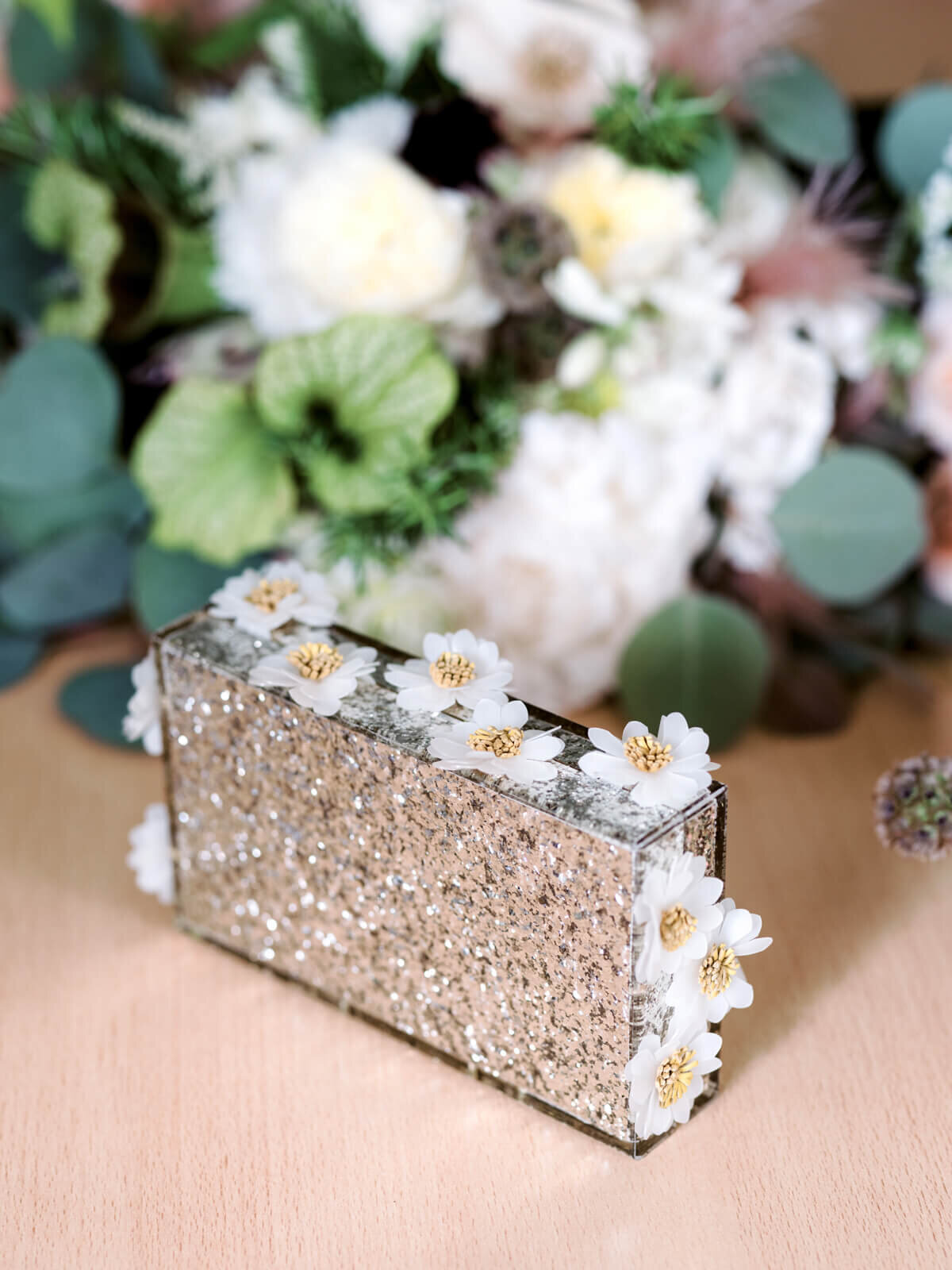A brown, rectangular case with flowers on the sides and a bouquet of flowers in the background