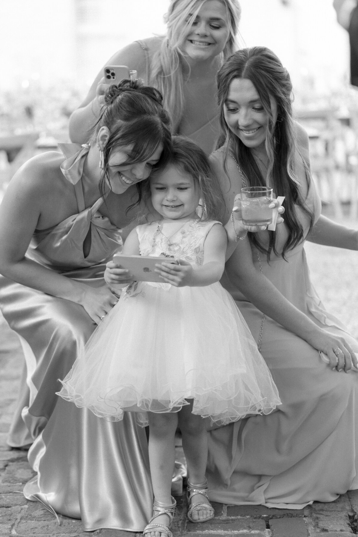 Cute flower girl takes a selfie with bridesmaids during spring wedding in Charleston. Candid black and white fun wedding photographer. Kailee DiMeglio Photography.