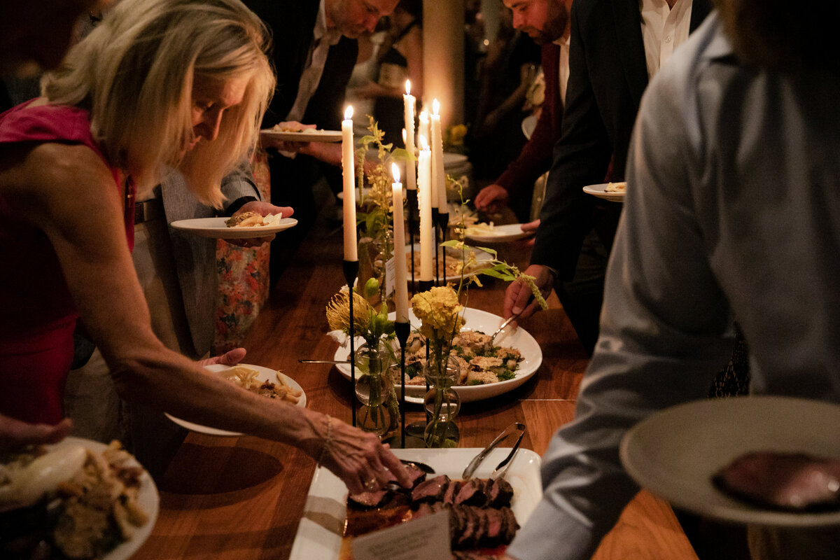 Chicago guests at Elske Restaurant wedding reception hold plates at romantic candlelit buffet