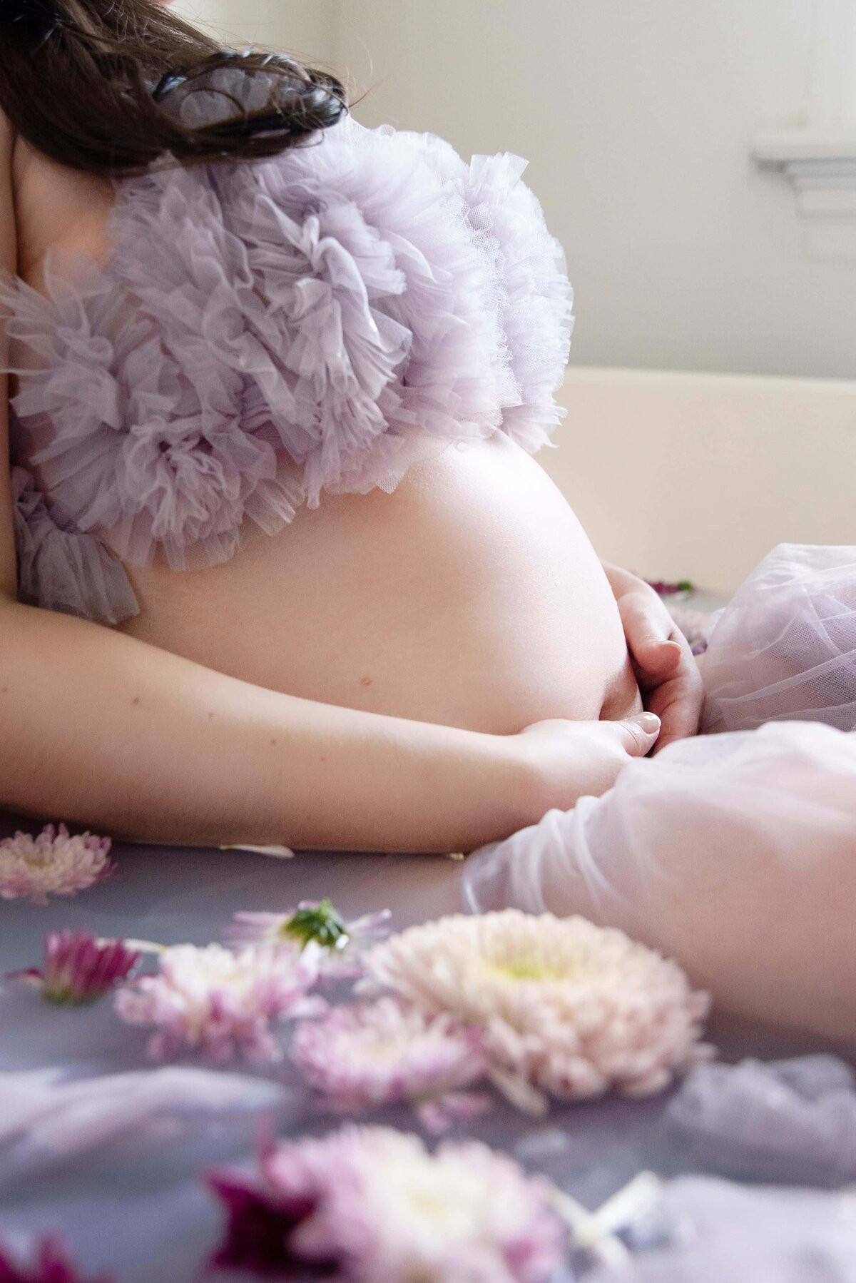 st-louis-maternity-photographer-close-up- of-pregnant-belly-in-milk-bath-with-purple-flowers